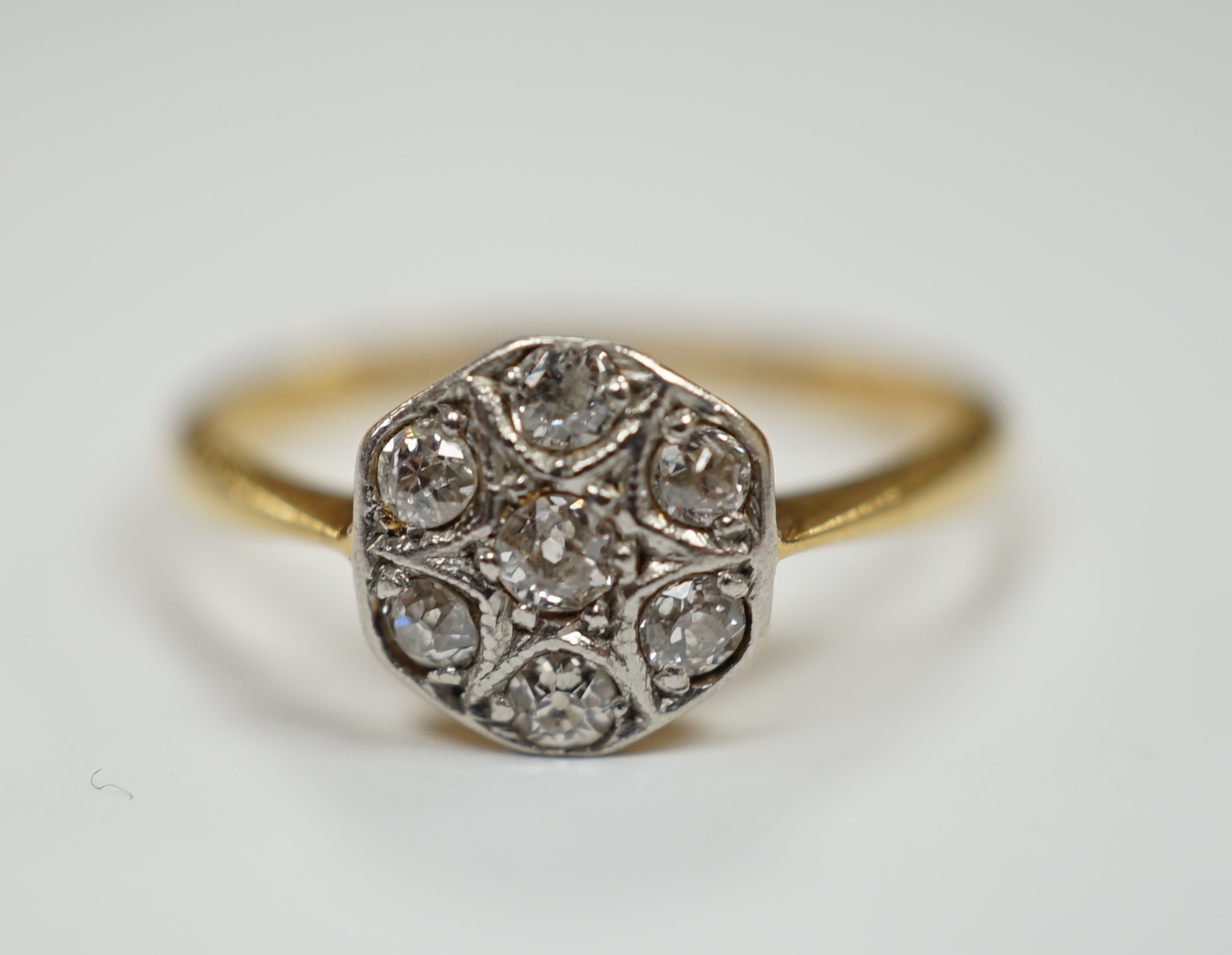 A 1920's 18ct, plat and seven stone diamond set cluster ring, size K, gross weight 2.2 grams.